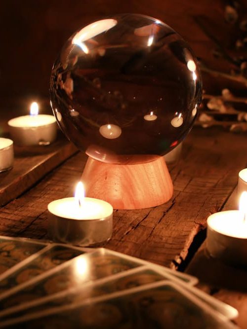 Boule de cristal entourée de bougies allumées, cartes étalées au premier plan